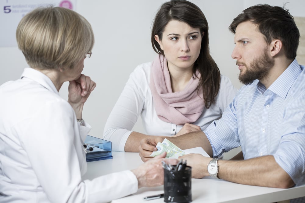 Young worried couple paying to experienced doctor for visit-1